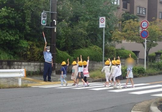 手を挙げて横断歩道を渡る小学生