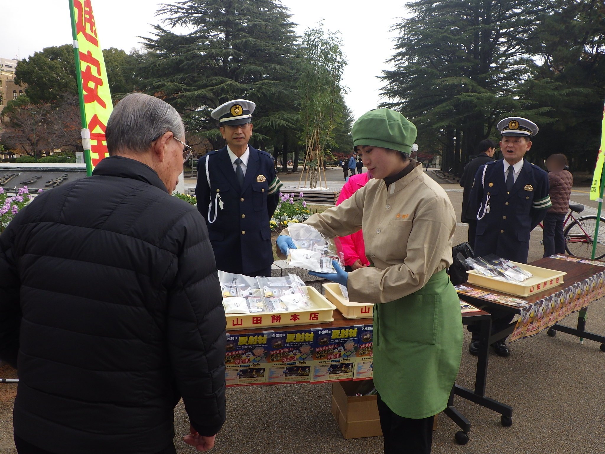 豆大福と反射材を渡す山田餅の従業員