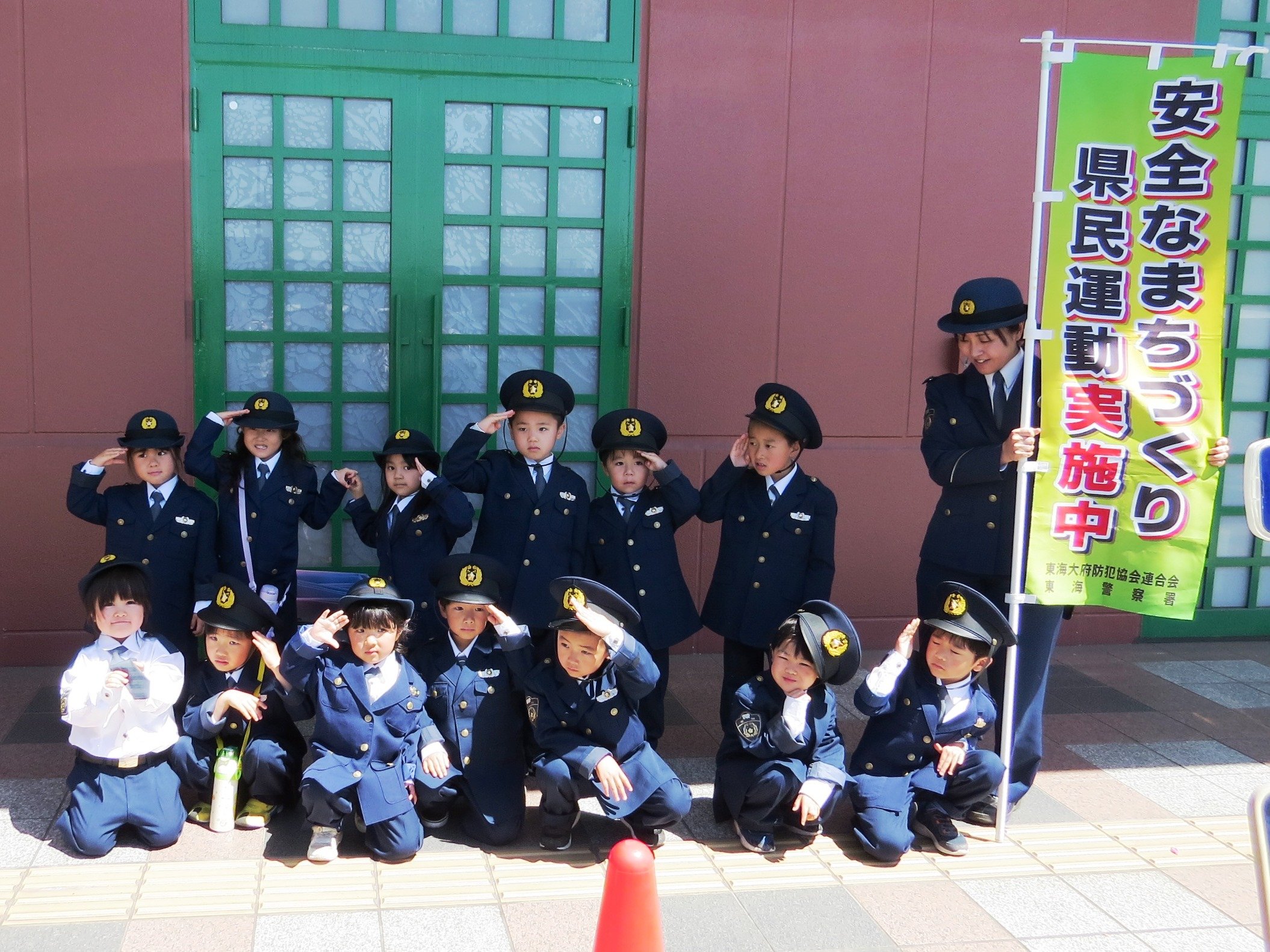 ちびっこ警察官が敬礼をして記念撮影している様子