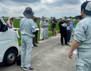 ほ場にて普及指導員の説明を熱心に聞く生産者