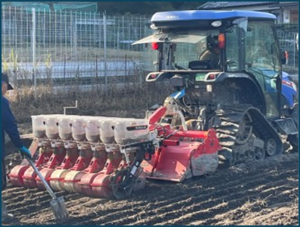 ほ場を走る播種機を取り付けたトラクター