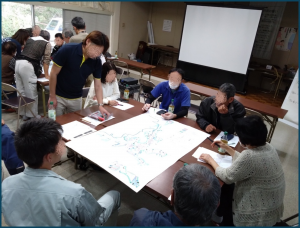 集会所の室内にて集落地図を囲み意見を交換する参加者