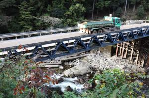 川の中に横倒しになったコンクリートと工事用道路